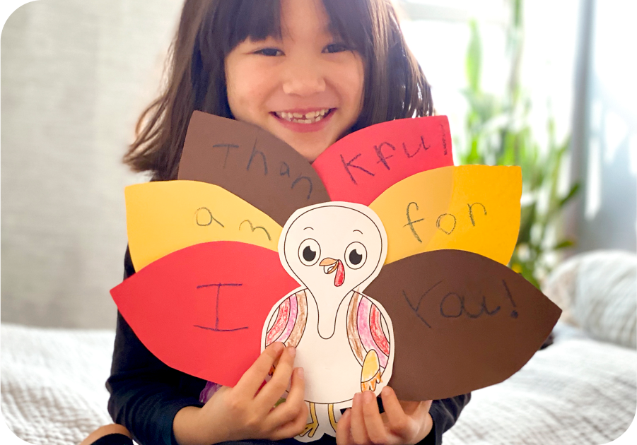 Child holding up completed Many Ways to Give Thanks printable