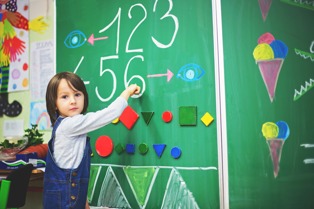 Preschool child doing number activity at blackboard