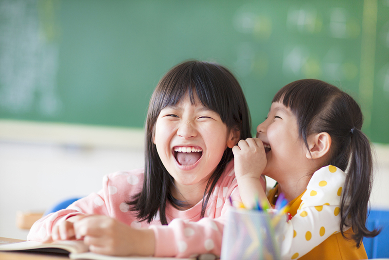 Two kids laughing together in class