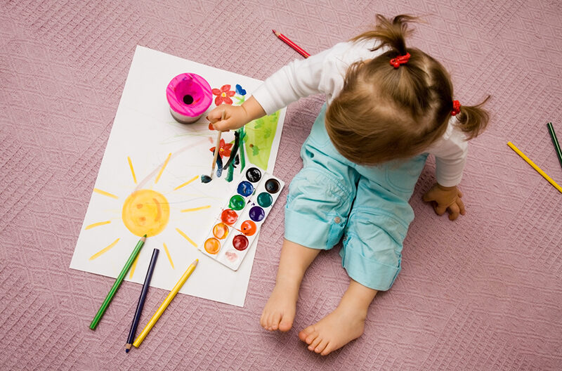 Young girl painting with watercolors on paper