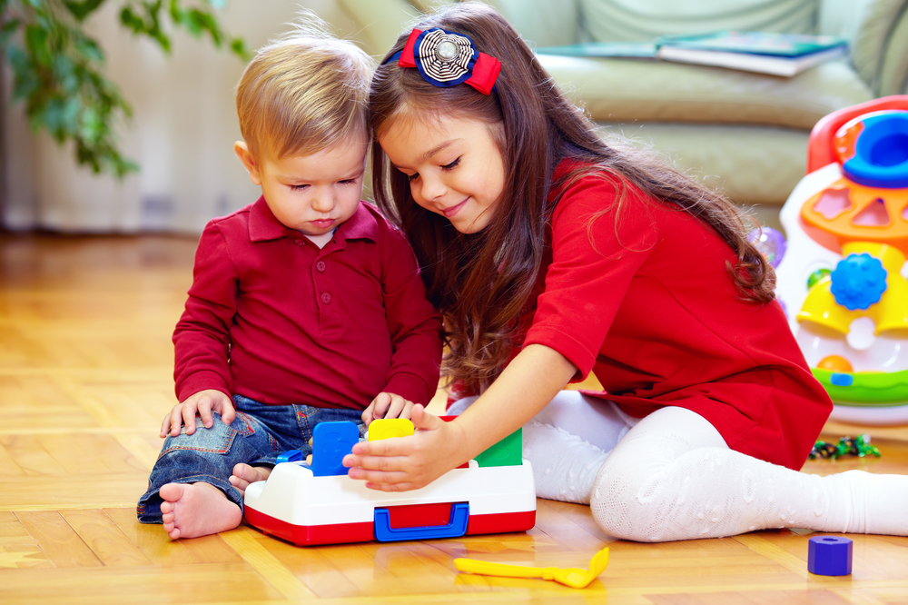 Girl playing with 2-year-old brother on floor