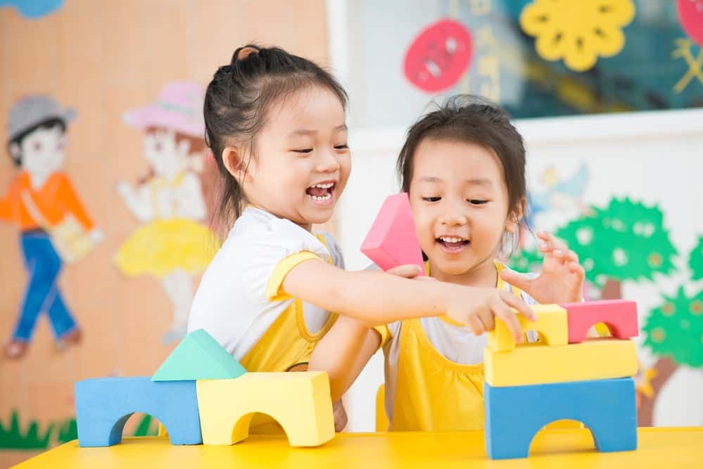 Two kids smiling and playing with blocks