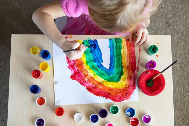 Child painting a rainbow for an indoor art show