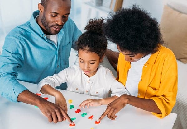 Parents playing with plastic numbers to help child learn