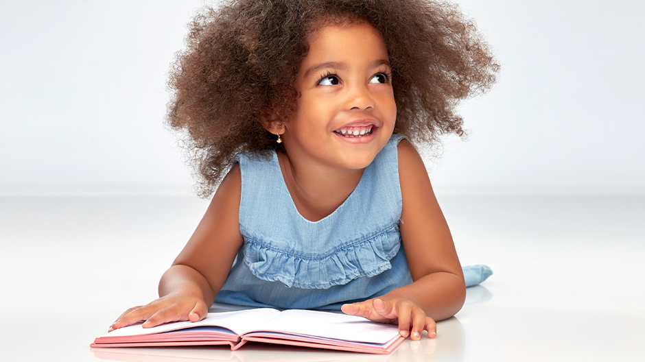 Motivated child on the floor learning from a book