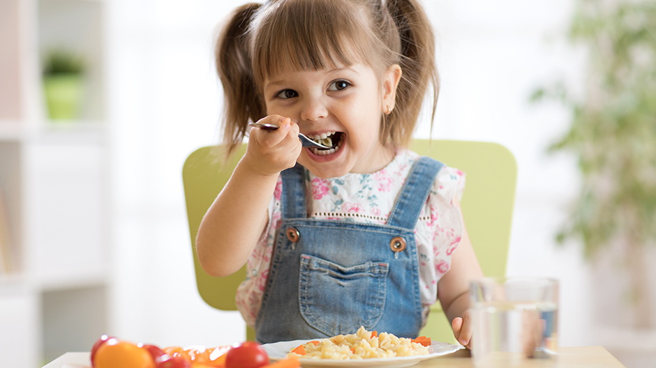 Child motivated to learn about new foods eating meal at table