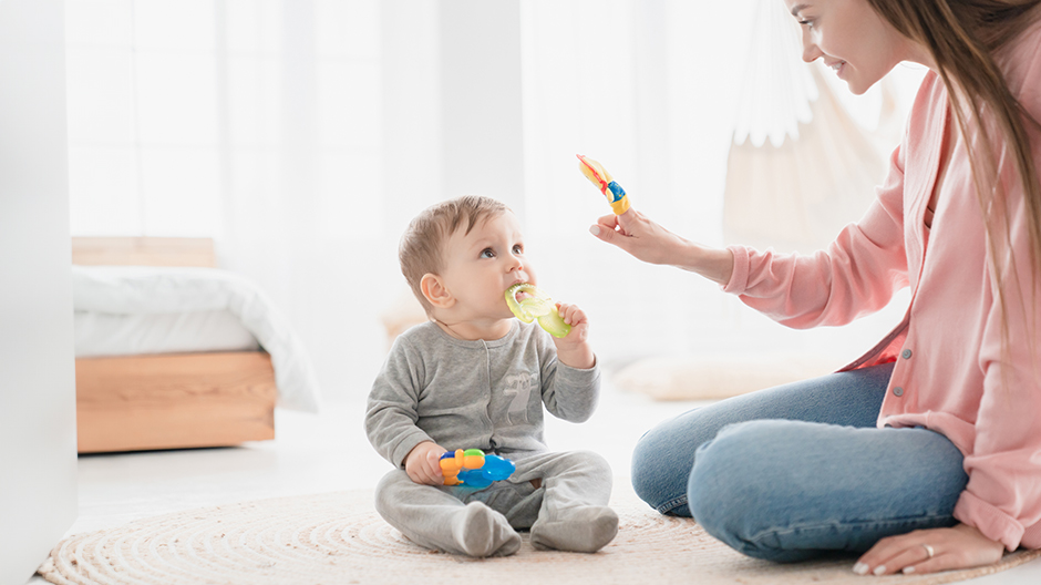Child-Brain-Development-1-Hero Baby playing on floor and looking at mom's raised hand