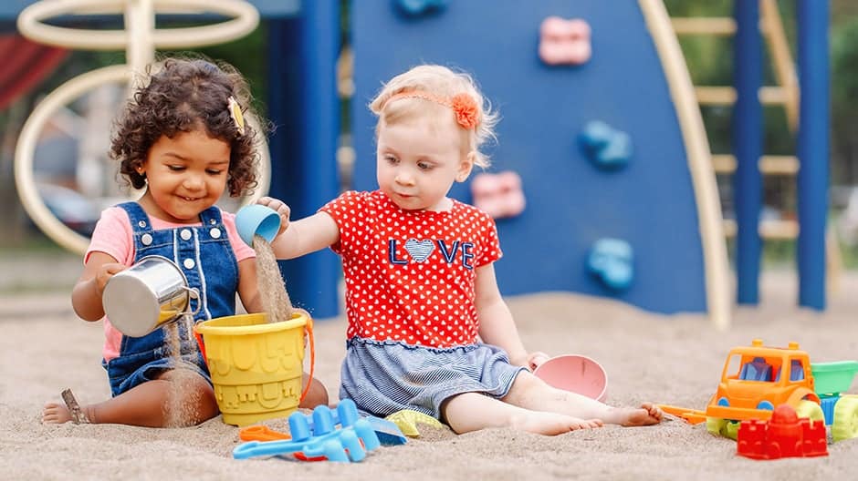 Toddlers playing together outside during daytime