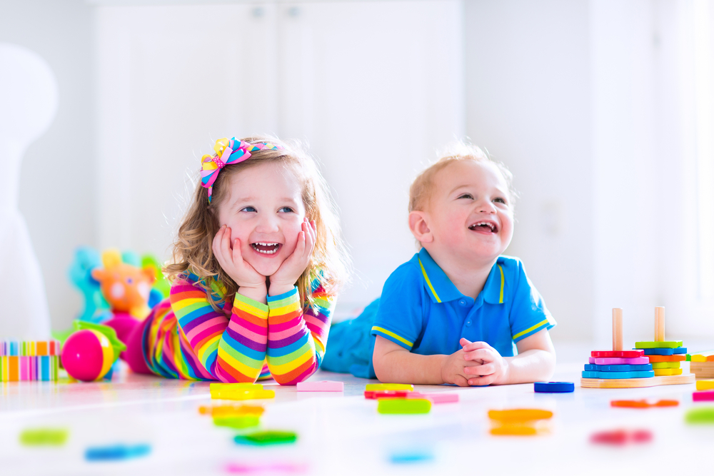 Two kids laying on the ground smiling