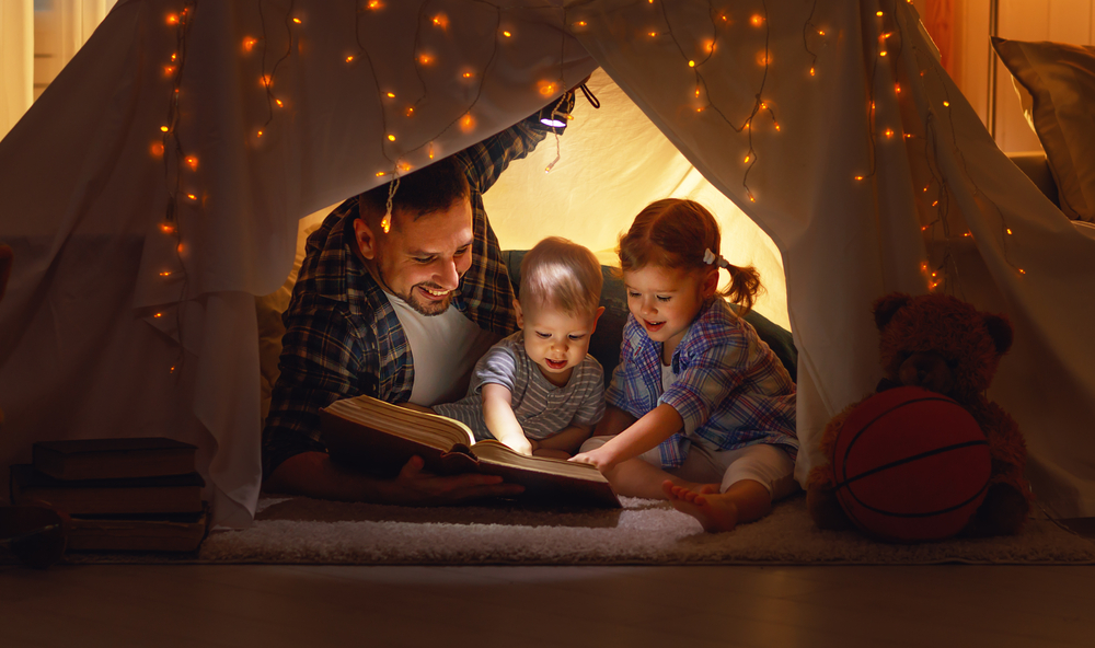 Dad reading to kids in a tent to show them calming strategies for kids