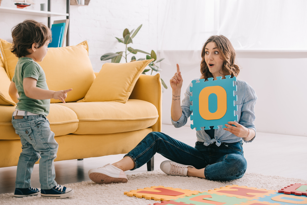 Parent working with kid on letter sounds using letter toys