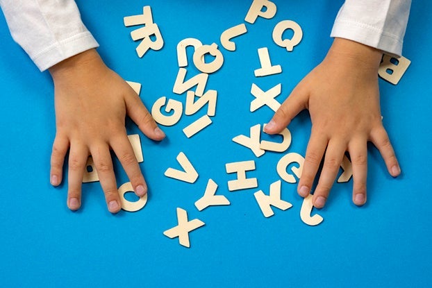 The child lays out the letters on the table. The concept of the school of education