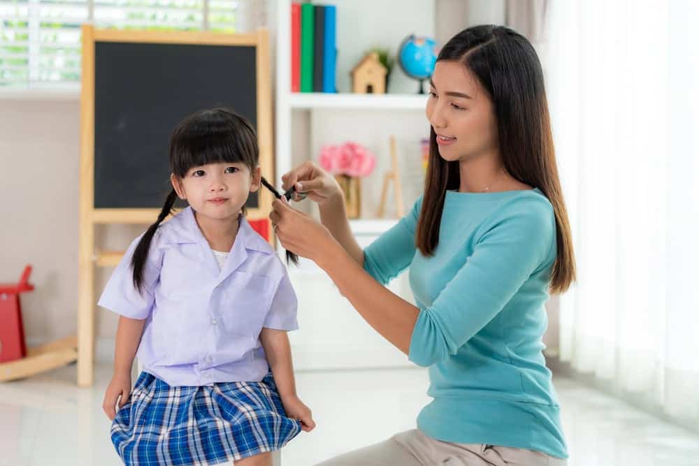 Mom doing daughters hair for her morning routine
